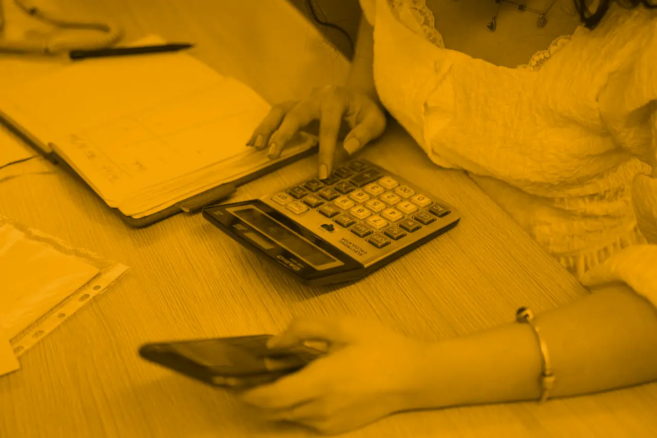 Person using calculator and phone while reviewing financial documents