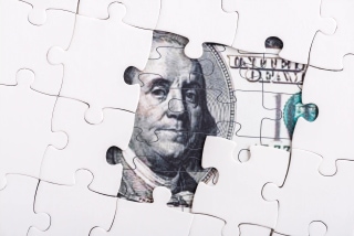 Puzzle pieces forming dollar bill representing hidden costs and fragmented HR processes