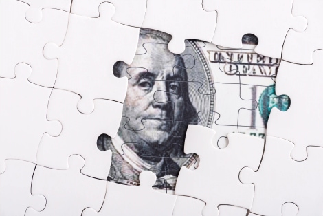 Puzzle pieces forming dollar bill representing hidden costs and fragmented HR processes