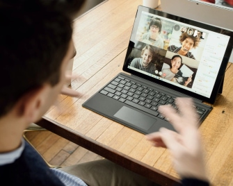 man speaking to 4 other people in a remote team in a video call on a laptop