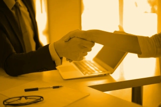 Handshake over a desk in an office