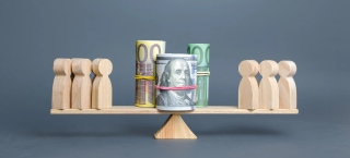 Wooden figures balanced with rolled banknotes on scale representing competitive fair pay and talent compensation